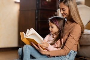 Portrait of happy mother and daughter reading book