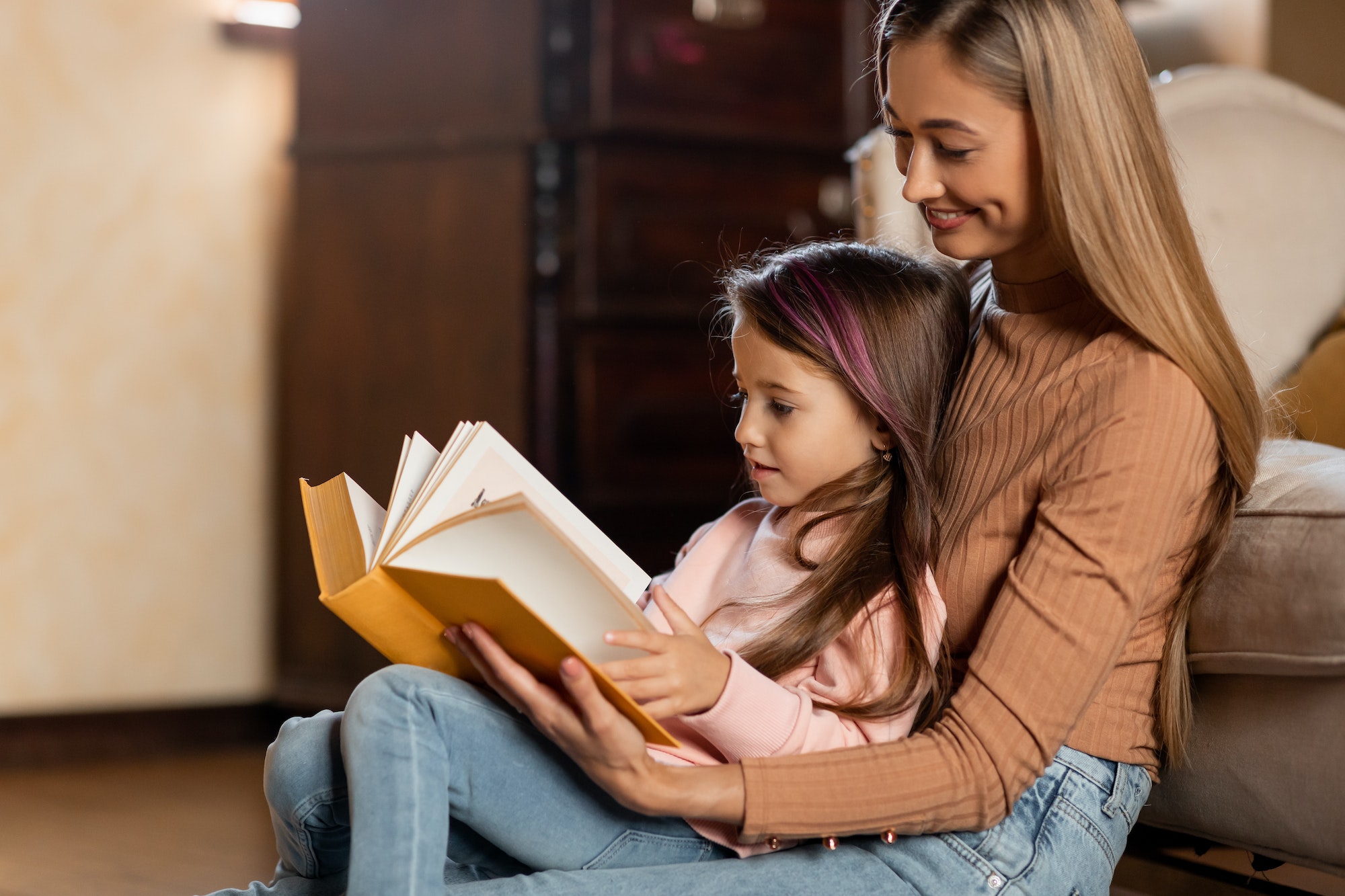 Portrait of happy mother and daughter reading book